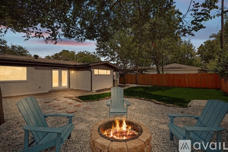 A backyard with a fire pit and chairs.