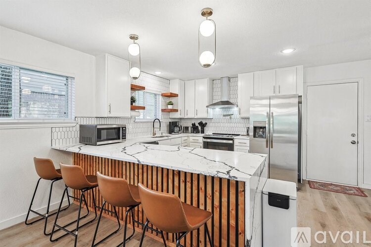 A kitchen with a white marble countertop and wooden bar stools.