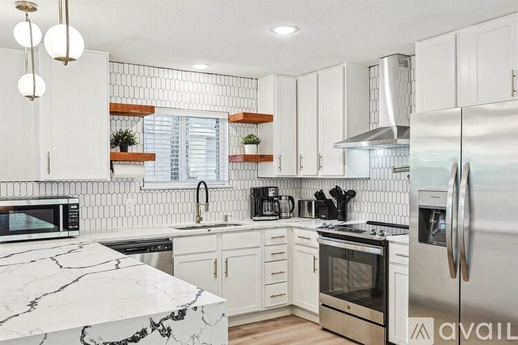 A kitchen with white cabinets and a marble countertop.
