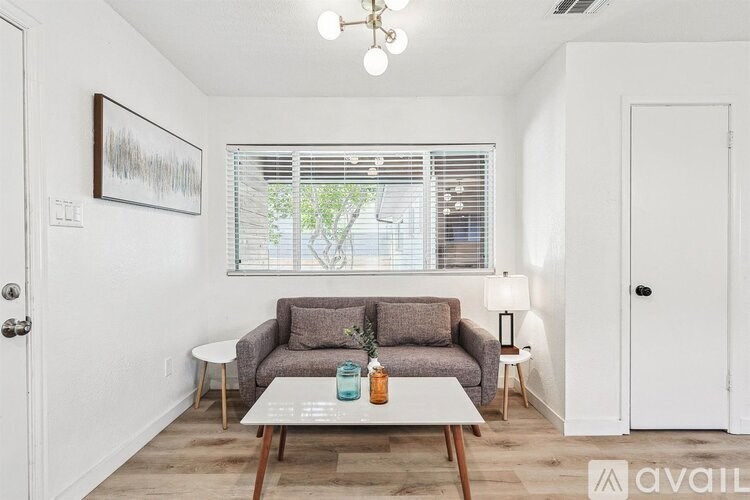 A living room with a grey couch, a white table, and a framed picture on the wall.