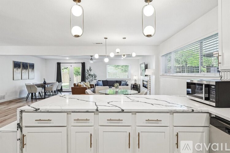 A modern kitchen with white cabinets and a marble countertop.