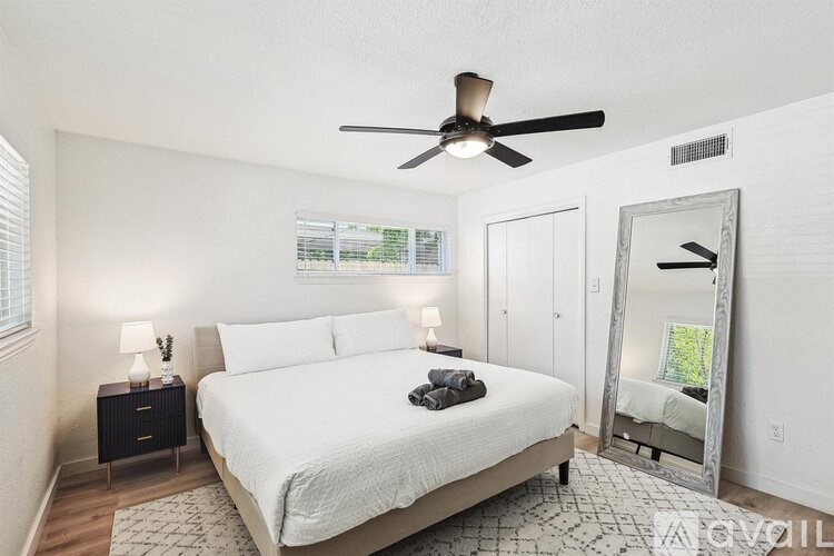 A bedroom with a bed, a ceiling fan, and a mirror.