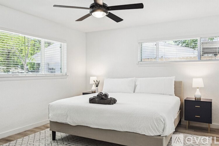 A bedroom with a bed, nightstand, and a ceiling fan.
