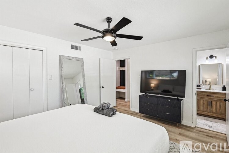 A bedroom with a bed, a television, and a ceiling fan.