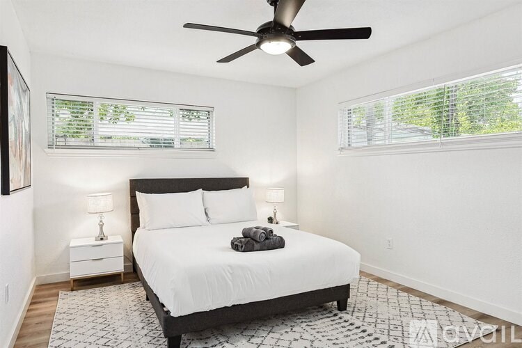 A bedroom with a bed, nightstands, and a ceiling fan.