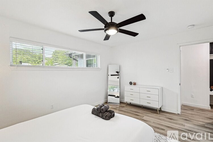 A bedroom with a white bed and a ceiling fan.