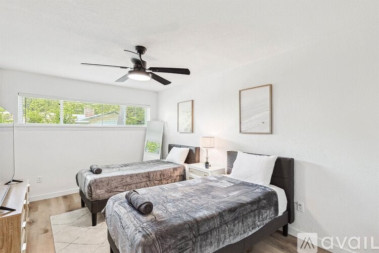 A bedroom with two beds and a ceiling fan.