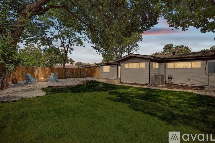 A backyard with a fence, lawn, and trees.