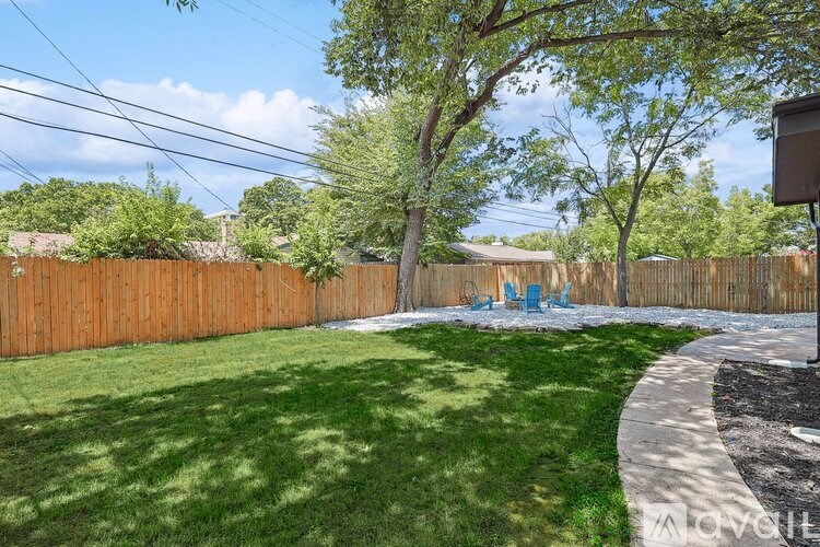 A backyard with a lawn, a tree, and a fence.