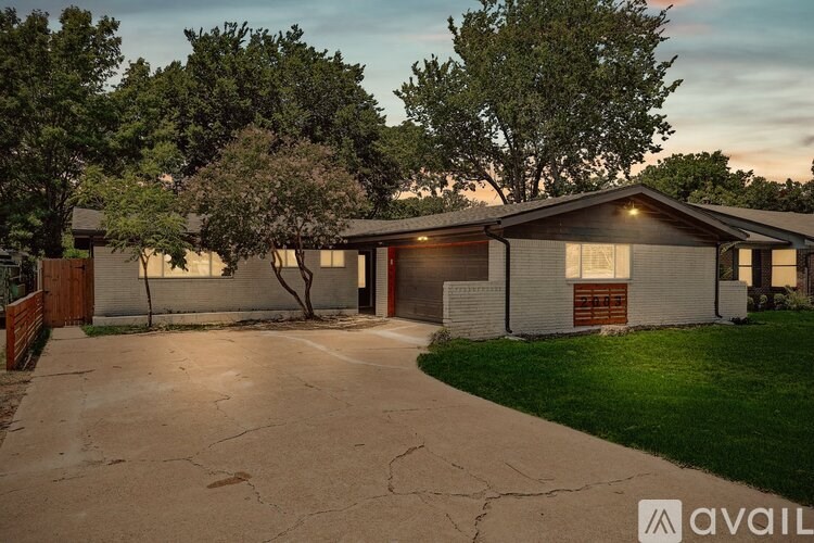 A house with a driveway and trees in the background.