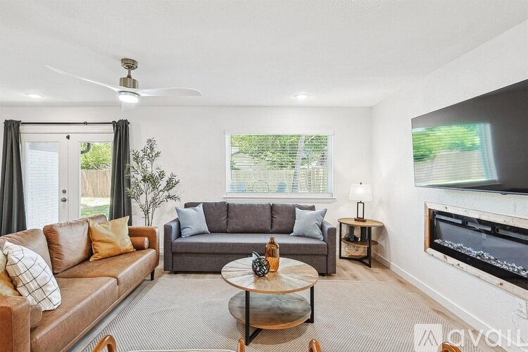 A living room with a brown couch, a coffee table, and a flat screen TV mounted on the wall.