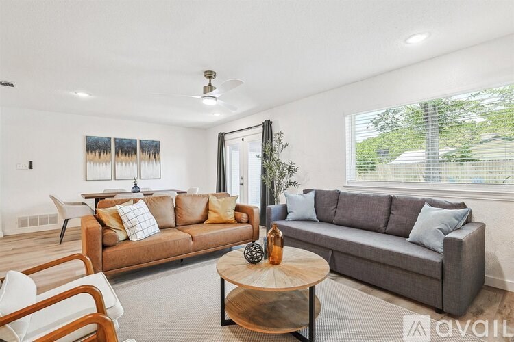 A living room with a grey couch, a wooden coffee table, and a painting on the wall.