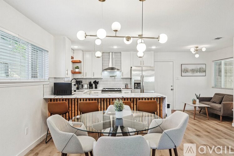 A modern kitchen with a glass dining table and chairs.