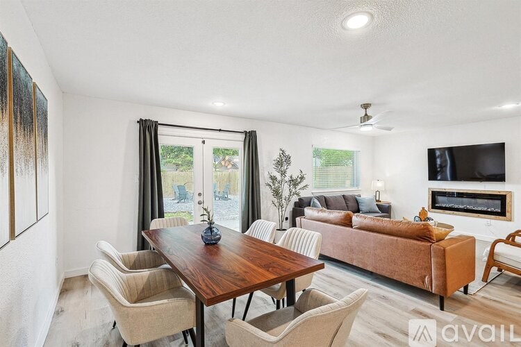 A living room with a brown table and chairs, a brown couch, and a television.