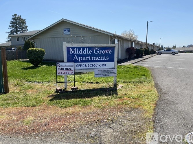 A sign for Middle Grove Apartments is displayed in front of a building.