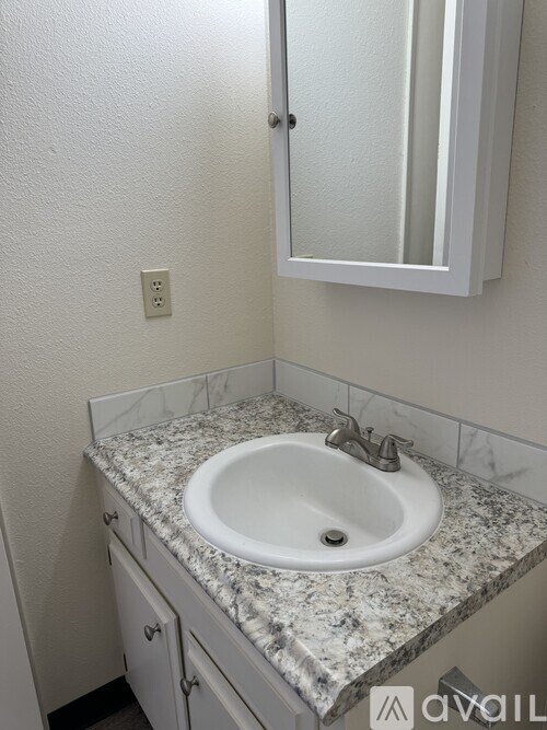 A bathroom with a granite countertop and a white sink.