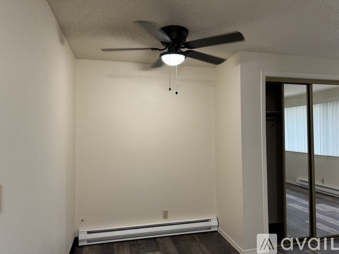 A room with a ceiling fan and a window with blinds.