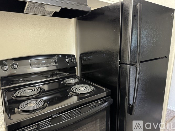 A black stove and refrigerator in a kitchen.