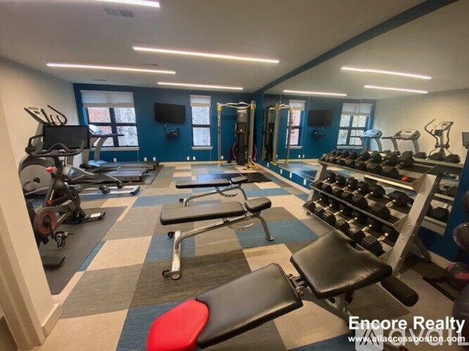 A gym with a variety of equipment including treadmills, weights, and exercise machines.