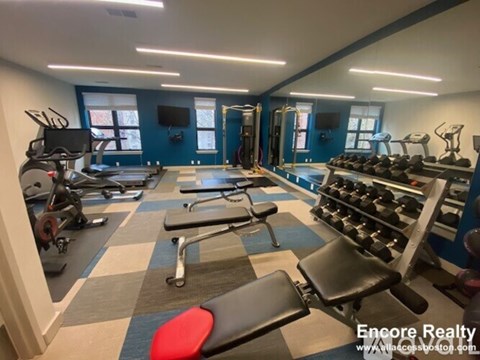 A gym with a variety of equipment including treadmills, weights, and exercise machines.