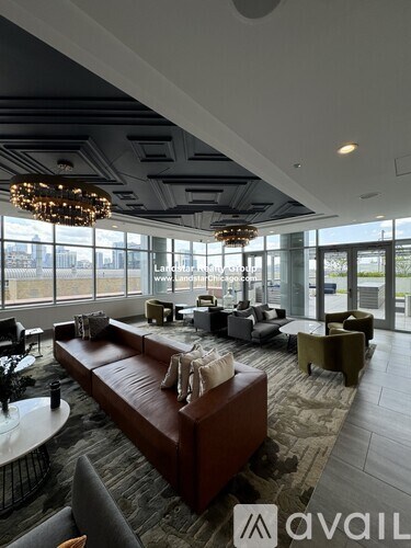 A modern living room with a large brown leather sofa and a chandelier.
