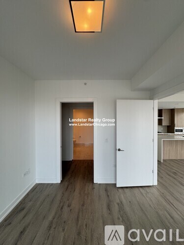 A room with a wooden floor and a white door leading to another room.