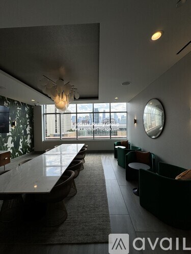 A modern living room with a long black couch and a large window.