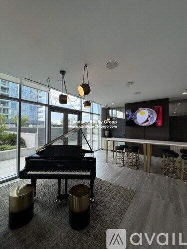 A grand piano is placed in a room with a glass wall and a bar area.
