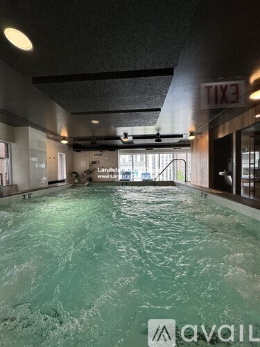 A large indoor swimming pool with a textured ceiling and a glass wall on the right side.