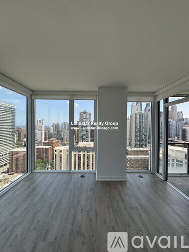 A room with wooden floors and a view of the city through large windows.