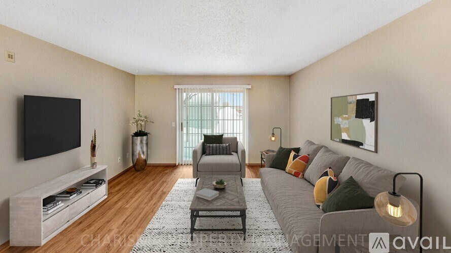 A living room with a grey couch, a black television, and a wooden floor.