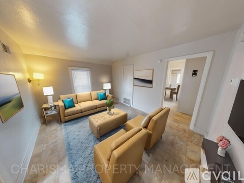 A living room with a tan couch and a blue rug.
