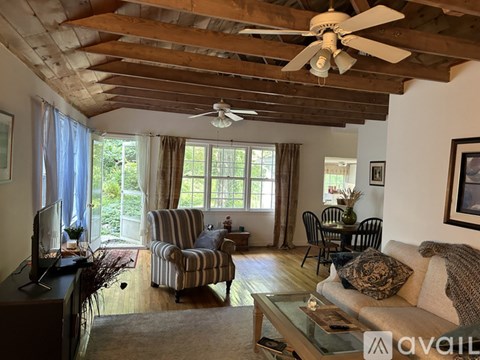 A living room with a striped chair and a ceiling fan.