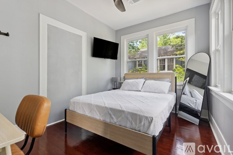 A bedroom with a bed, chair, and window.
