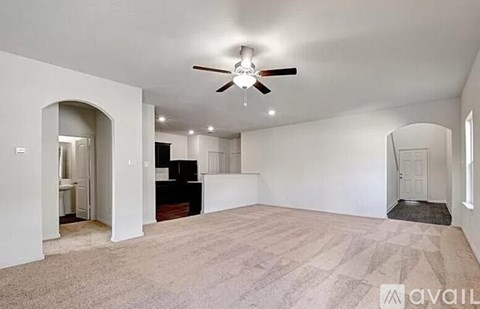 A spacious room with a ceiling fan and carpeted floor.