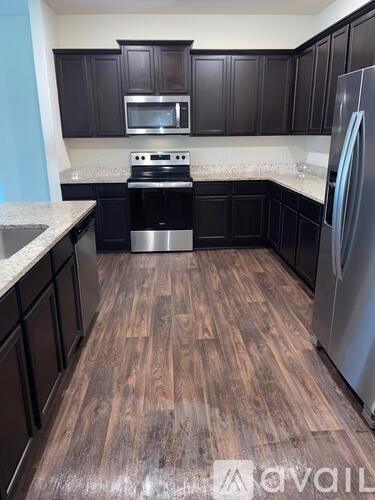 A kitchen with dark wood cabinets and a stainless steel refrigerator.
