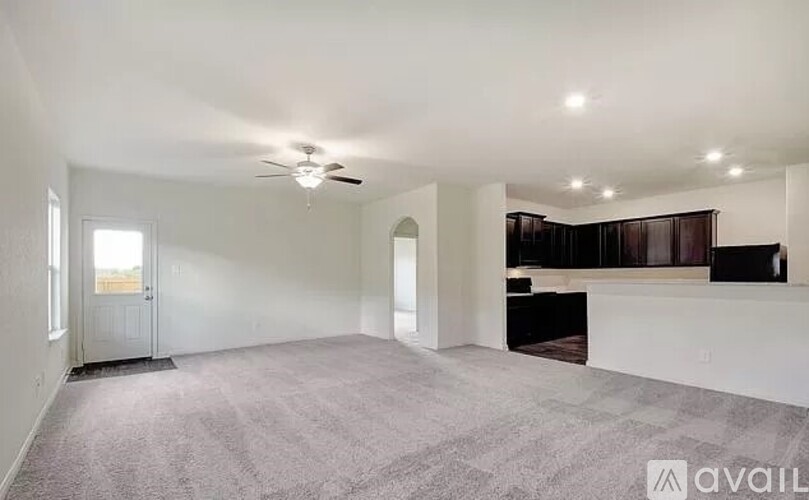 A spacious living room with a carpeted floor and a ceiling fan.