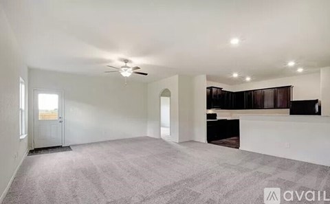 A spacious living room with a carpeted floor and a ceiling fan.
