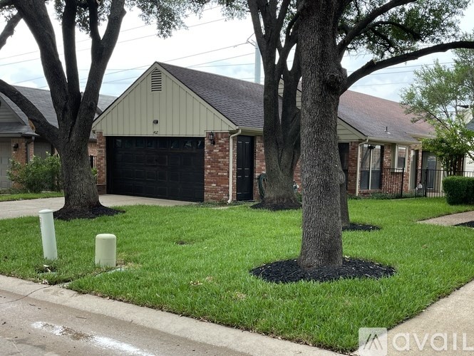 A house with a black garage door and a tree in front.