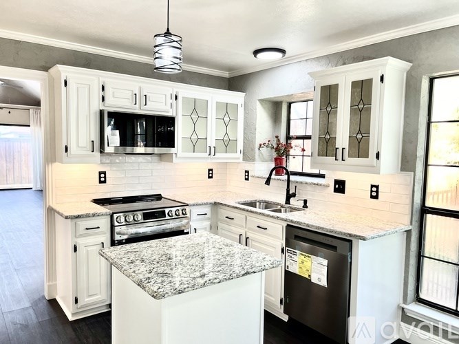 A kitchen with white cabinets and granite countertops.