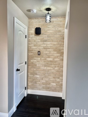A hallway with a brick wall and a white door.
