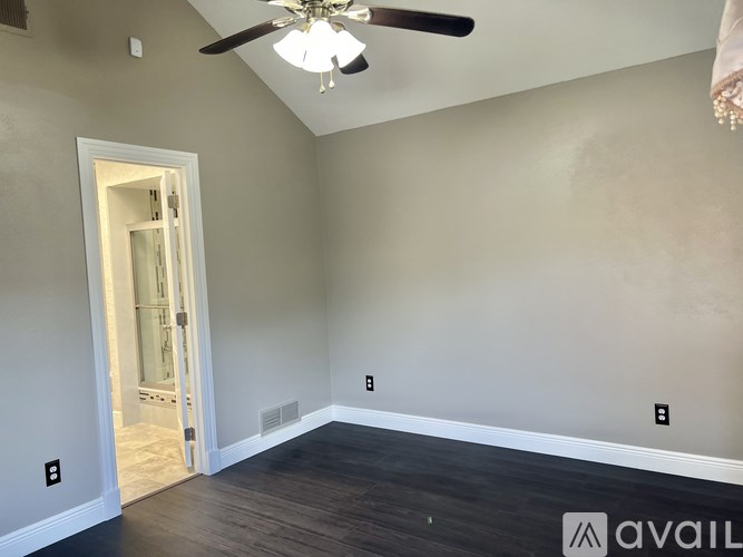 A room with a ceiling fan and a door leading to a hallway.