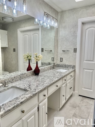 A bathroom with a marble countertop and a chandelier.