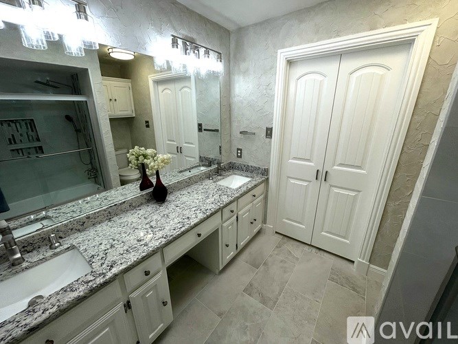 A bathroom with a marble countertop and white cabinets.