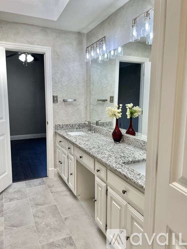A bathroom with a marble countertop and a large mirror.
