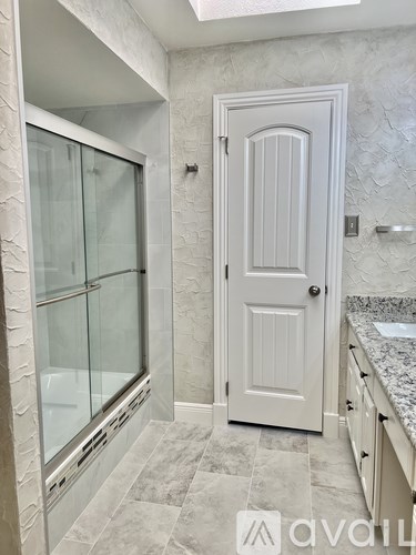 A white door is in a bathroom with a glass shower door.