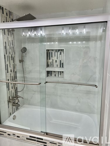 A modern bathroom with a glass shower enclosure and a white bathtub.