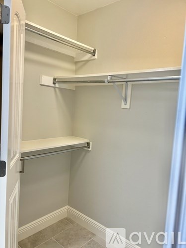 A white closet with two shelves and a white door.