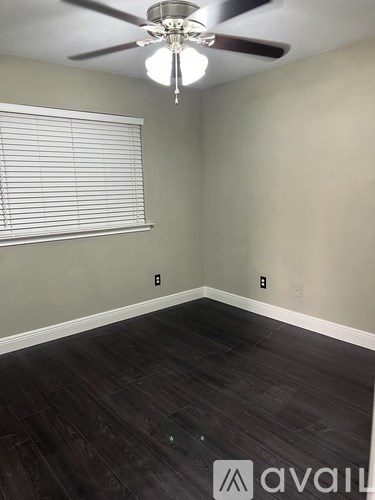 A room with a ceiling fan and a window with blinds.