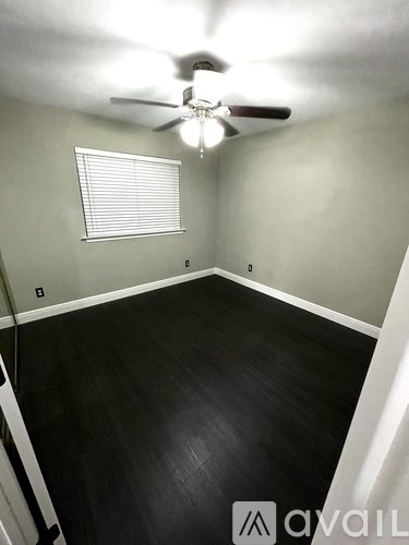 A room with a ceiling fan and a window with blinds.